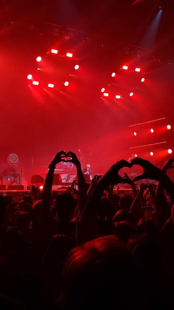 fans making heart shapes showing why live concerts are popular
